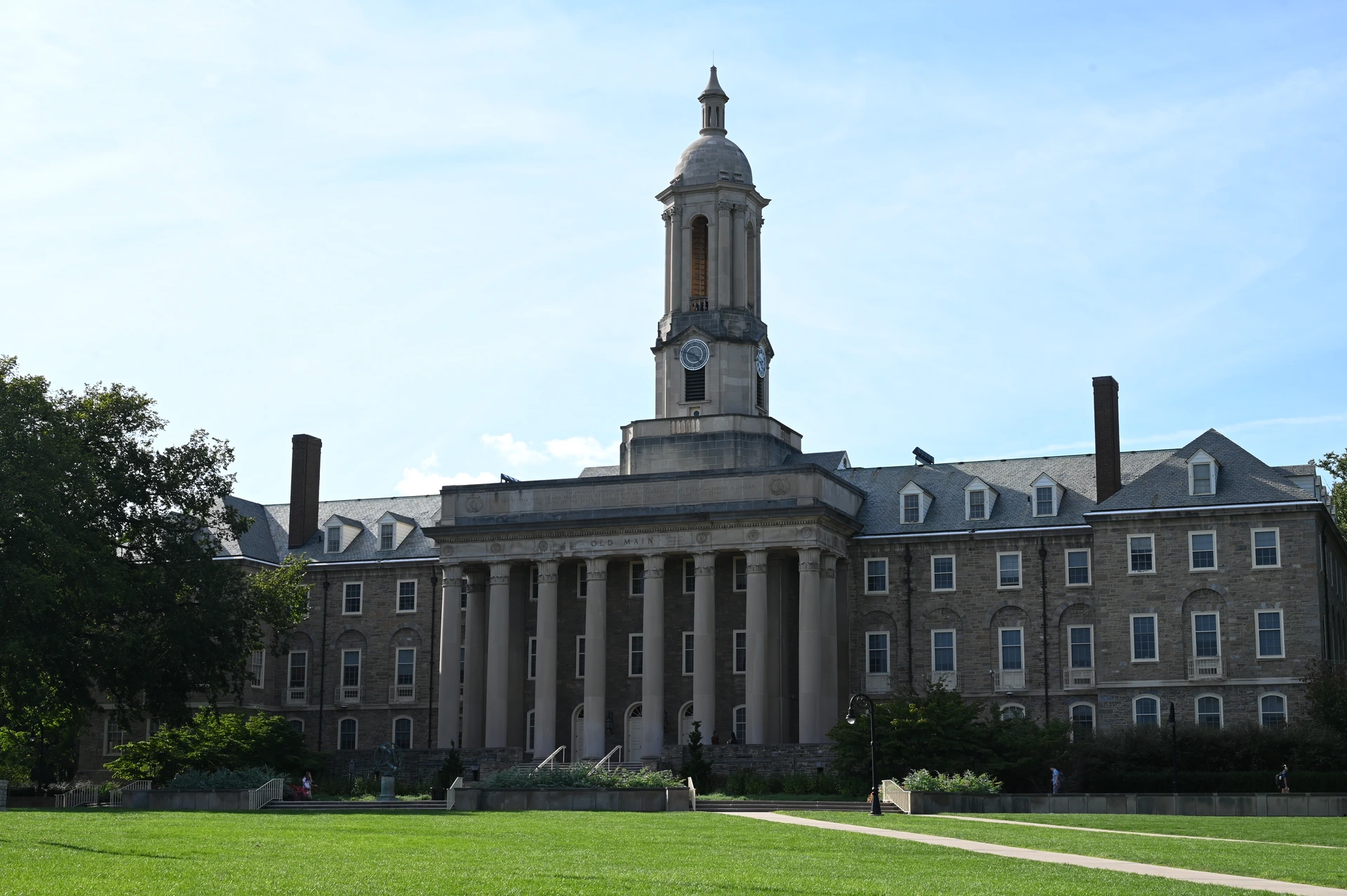 Old Main at Penn State, photographed across the lawn beneath a blue sky